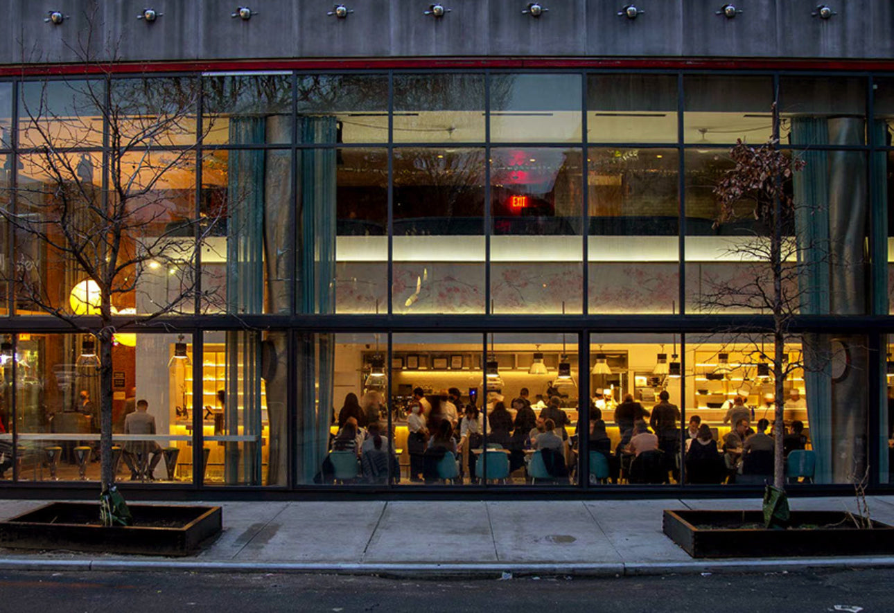 People inside a modern building with large glass windows at night.