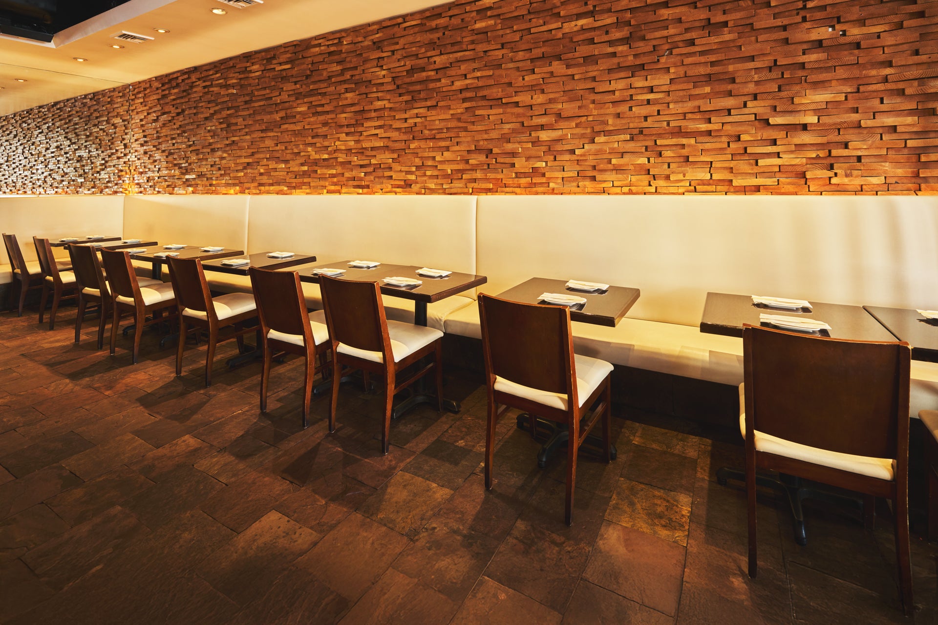 Dining area with wooden tables and chairs against a brick wall.