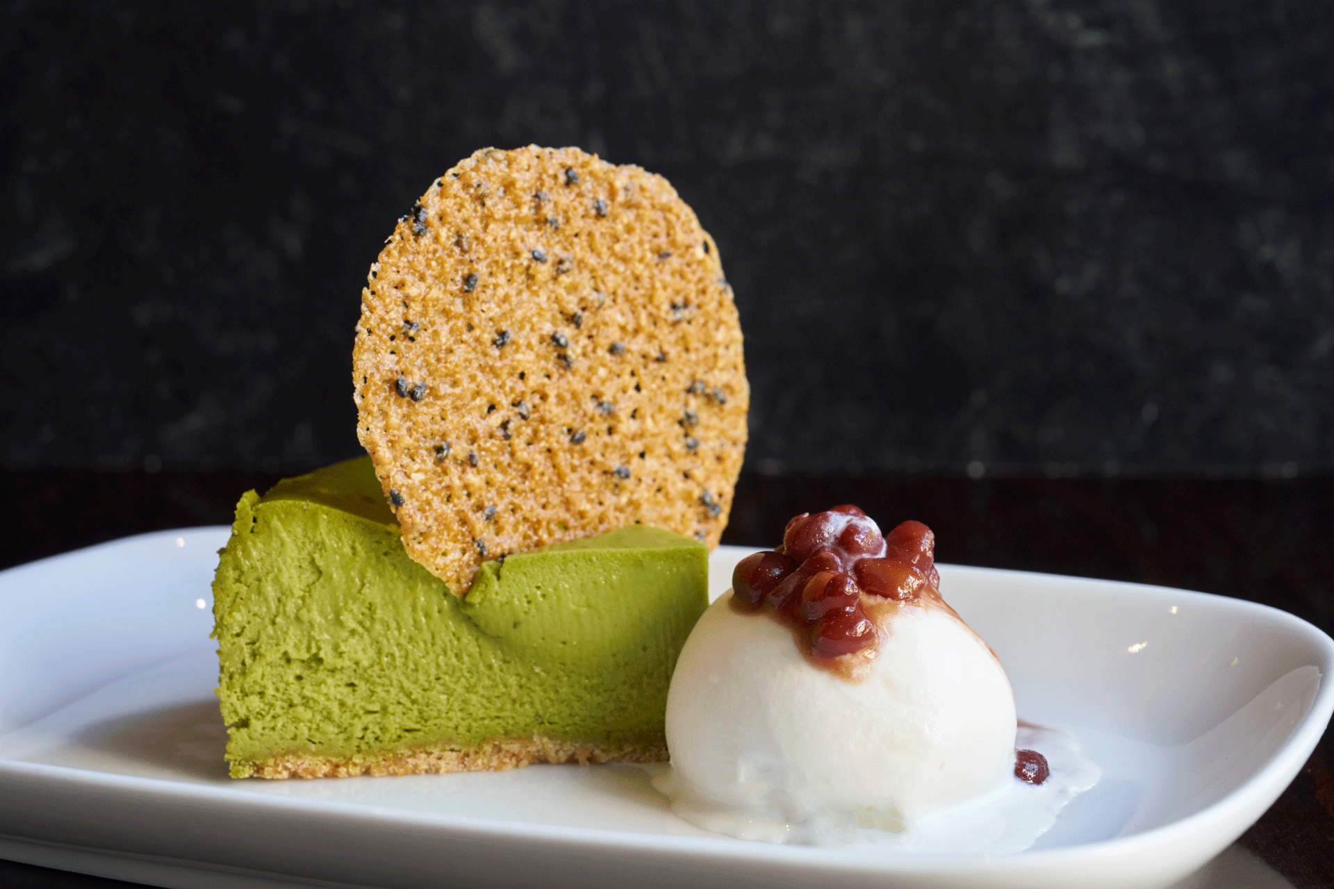Matcha green tea mousse dessert with sesame tuile and red bean.