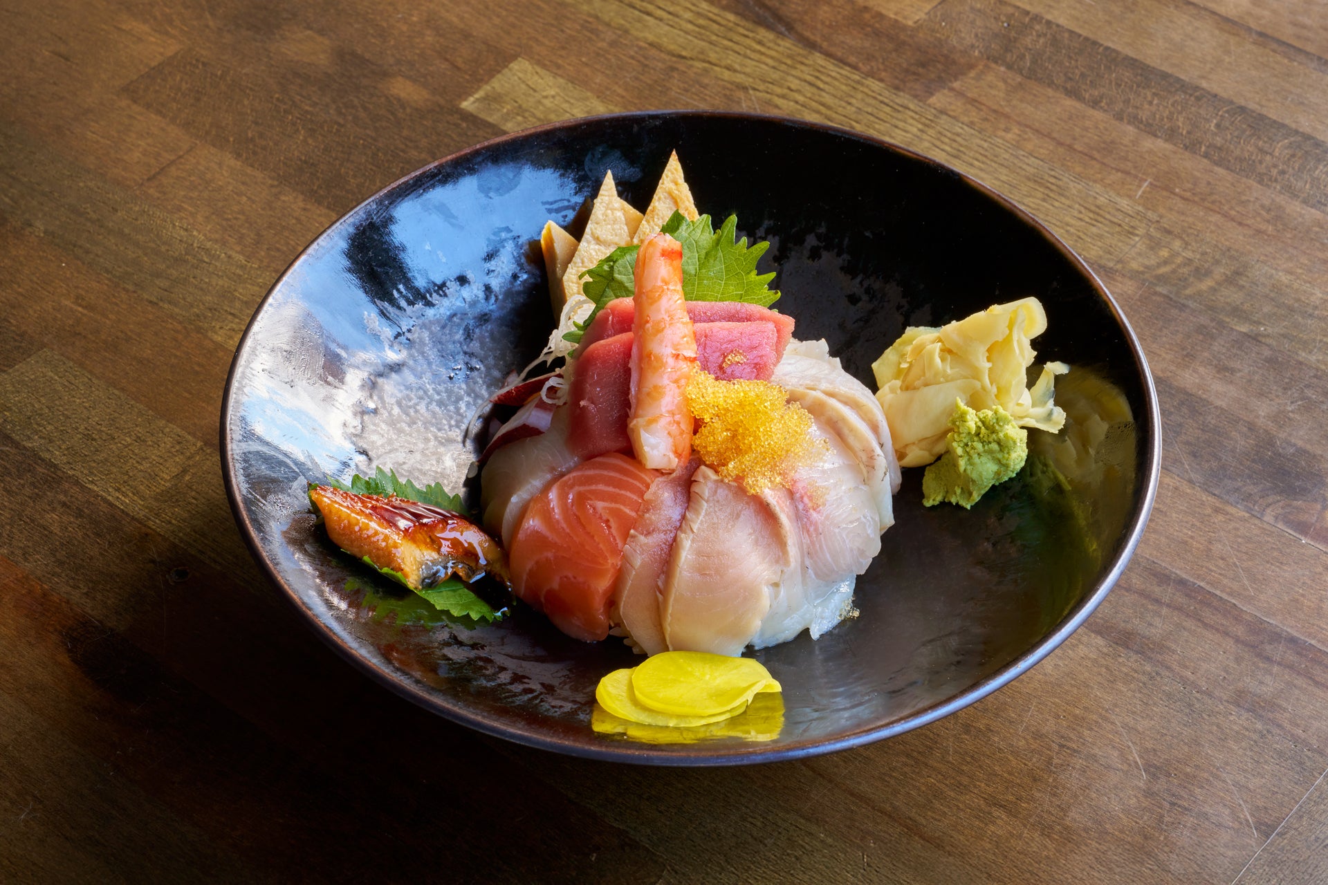 Colorful chirashi sushi bowl with assorted sashimi and vegetables.
