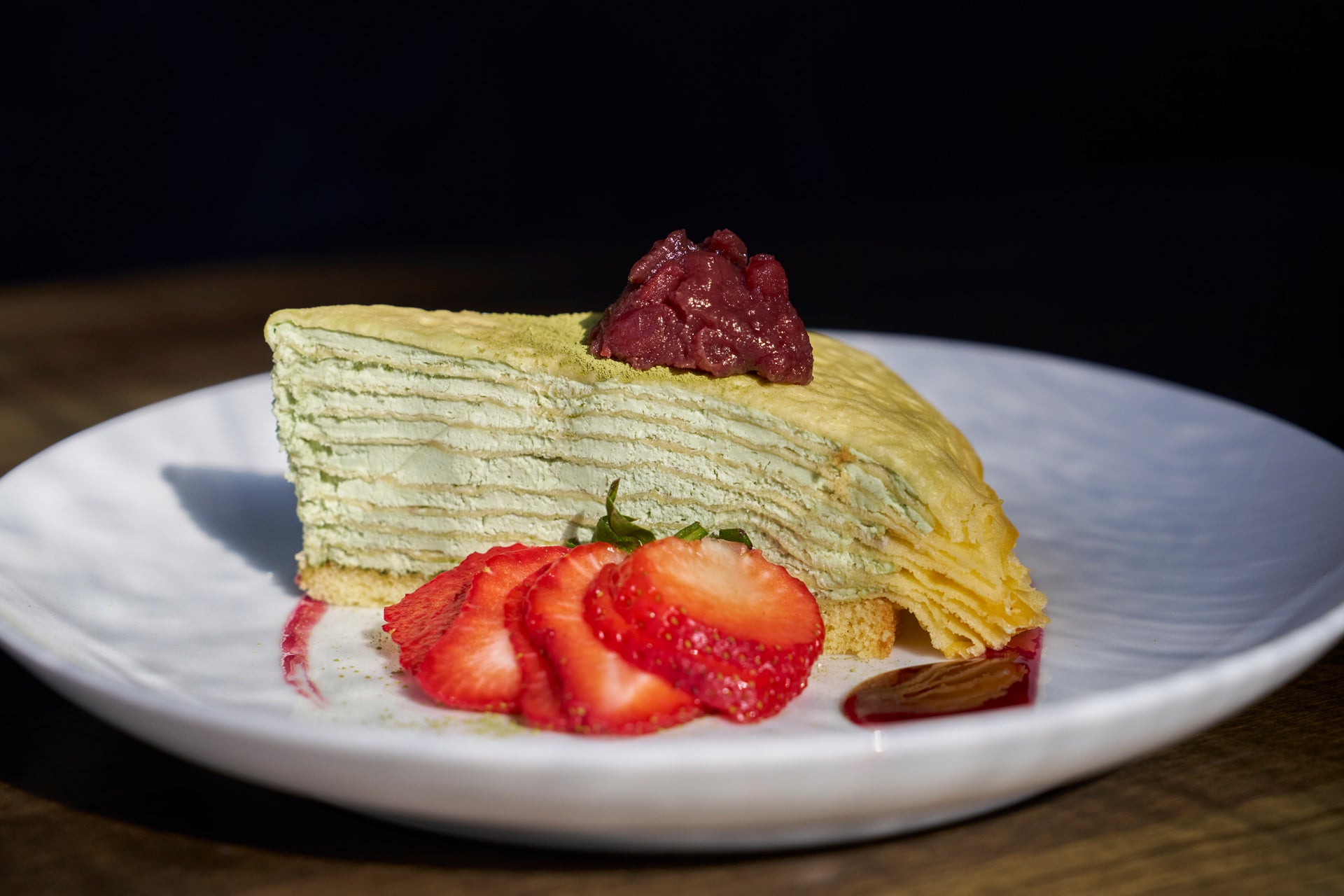 Slice of crepe cake with strawberries on a white plate