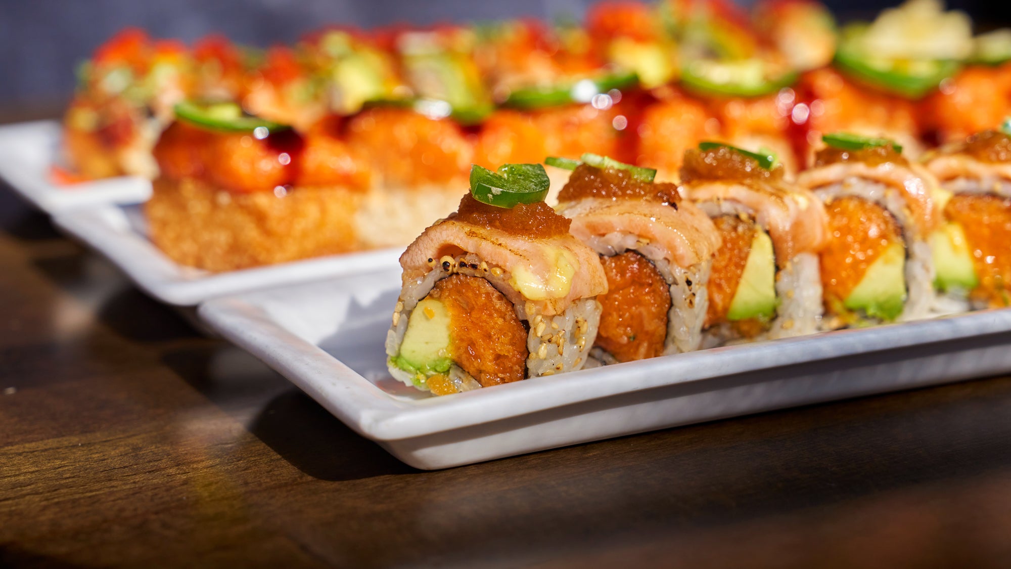 Platter of sushi rolls with avocado and crab on a wooden table