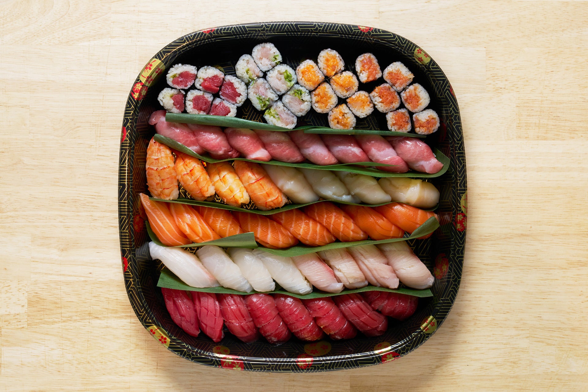 Assorted sushi on a decorative black plate on a wooden surface